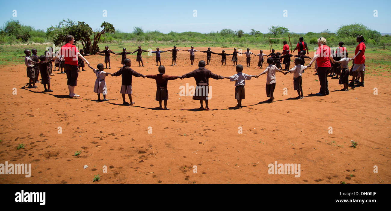 School kids and teachers playing hokey cokey in a Kenyan playground Stock Photo