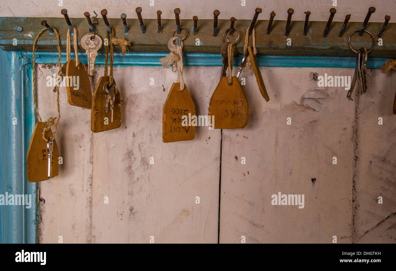 Keys and tags hanging from nails above a school cupboard door Kenya Stock Photo