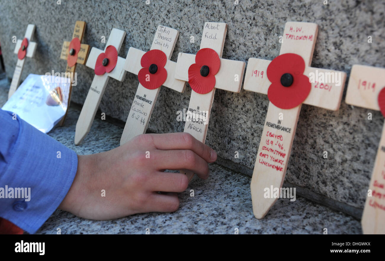 REMEMBRANCE CROSSES WITH POPPIES BEING PLACED AT WAR MEMORIAL RE ARMISTICE DAY WAR CONFLICT DEATH HEROES WORLD  WAR POPPY MEN UK Stock Photo