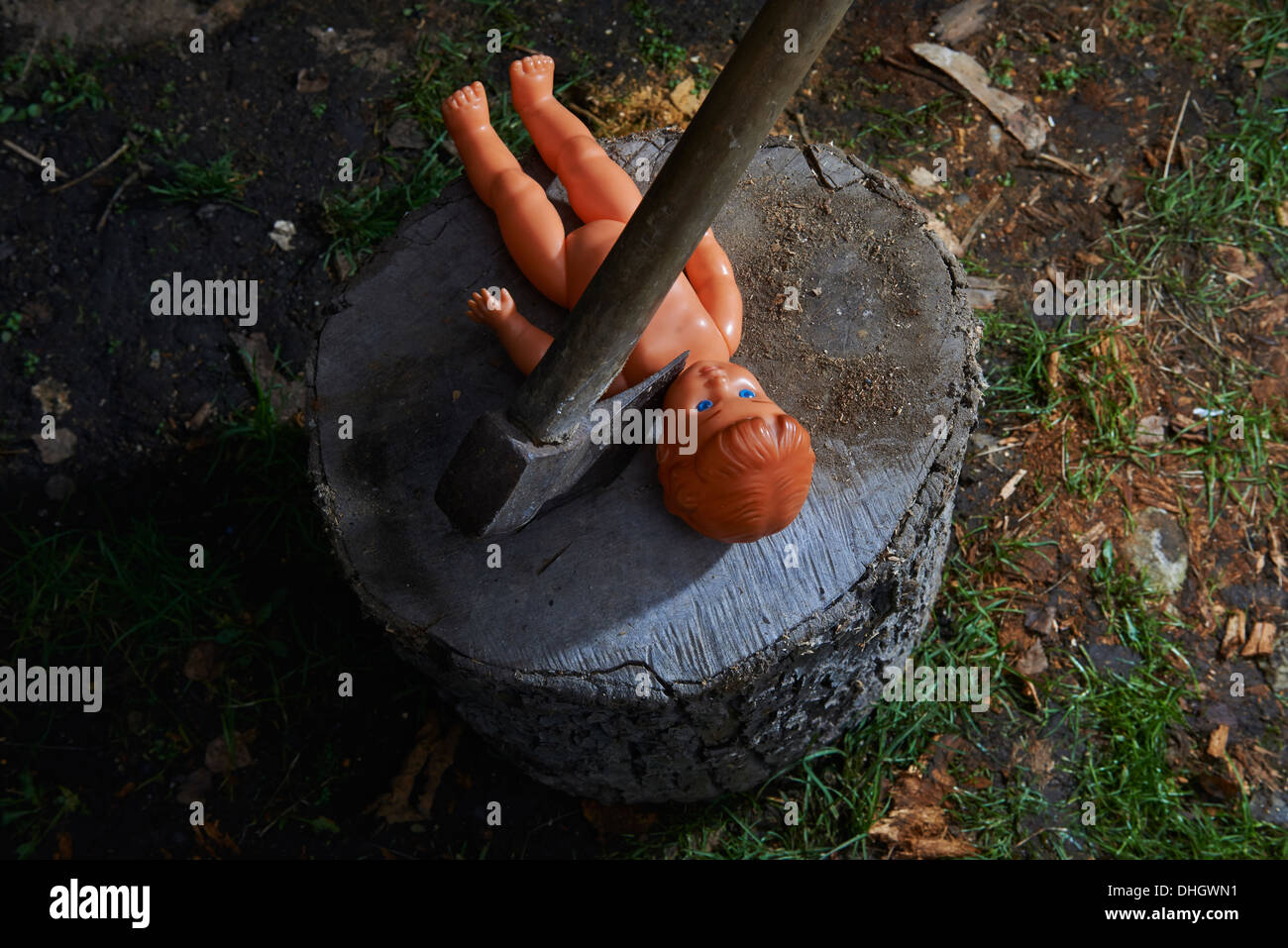 Execution - murder of child toy plastic baby doll with an ax Stock Photo
