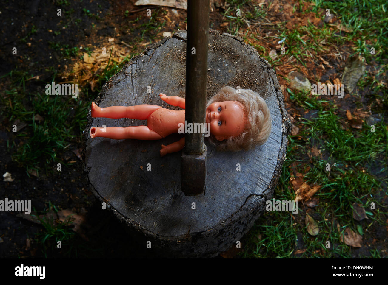 Execution - murder of child toy plastic baby doll with an ax Stock Photo