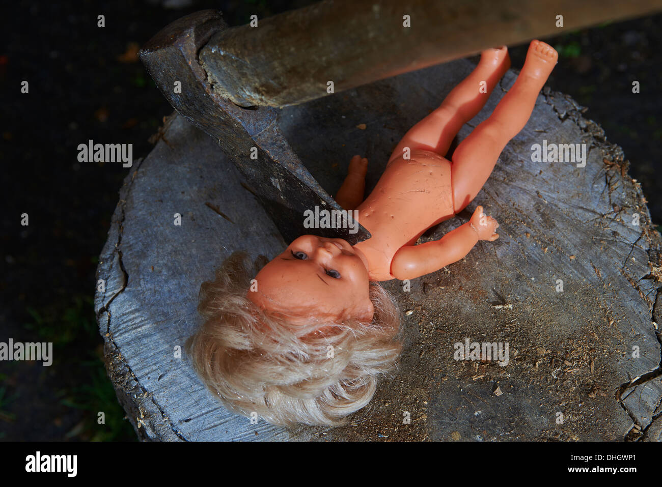 Execution - murder of child toy plastic baby doll with an ax, beheaded Stock Photo