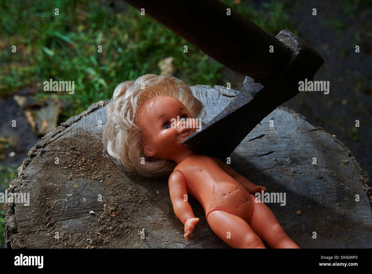 Execution - murder of child toy plastic baby doll with an ax, beheaded Stock Photo