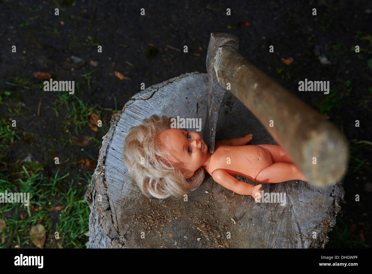 Execution - murder of child toy plastic baby doll with an ax, beheaded Stock Photo