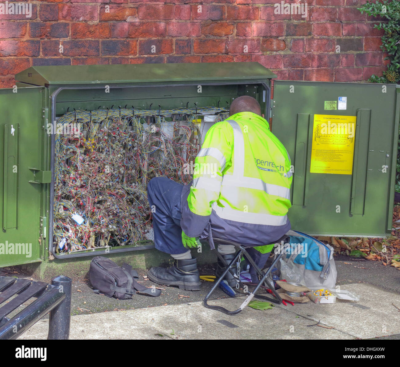 BT Openreach telecoms engineer fixing fault in green roadside box Stock Photo