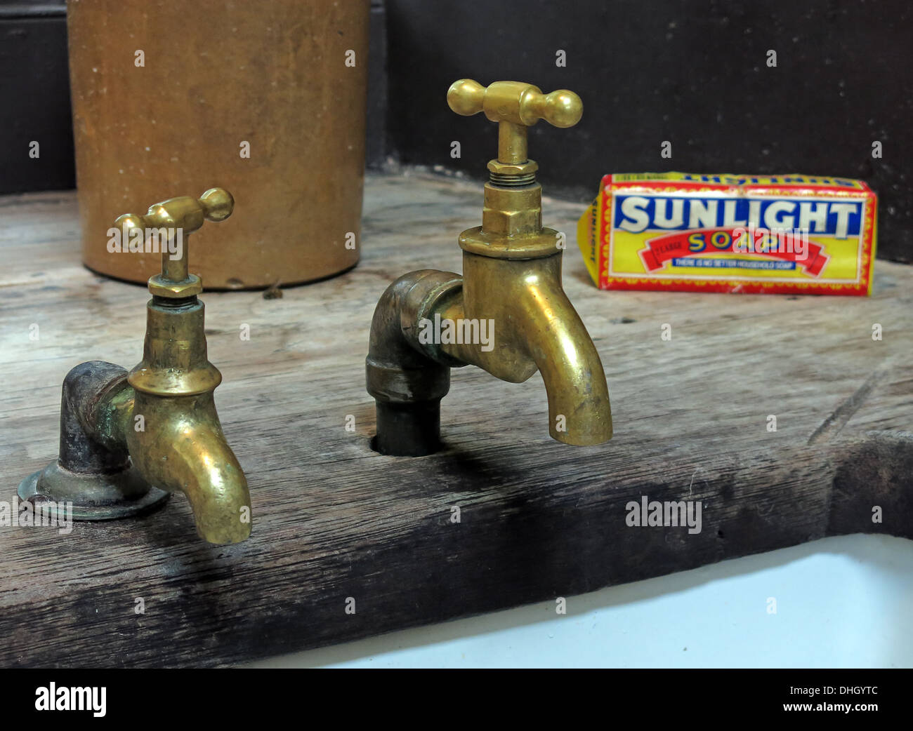 Two old historic Victorian brass taps, Lever Sunlight soap over a Belfast sink in England, UK Stock Photo
