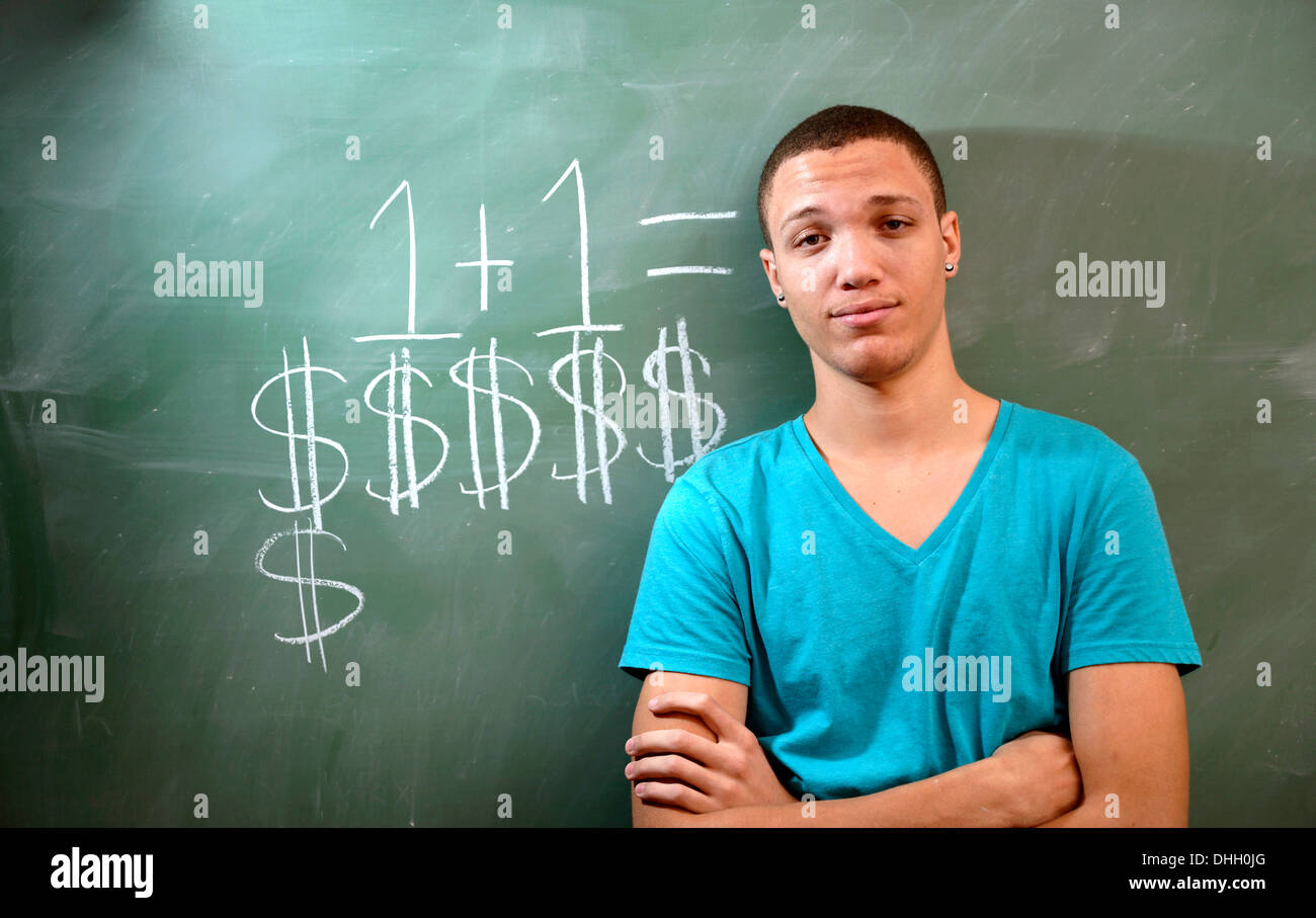 A young man on a college campus with a chalkboard and a comment about the cost of education. Stock Photo