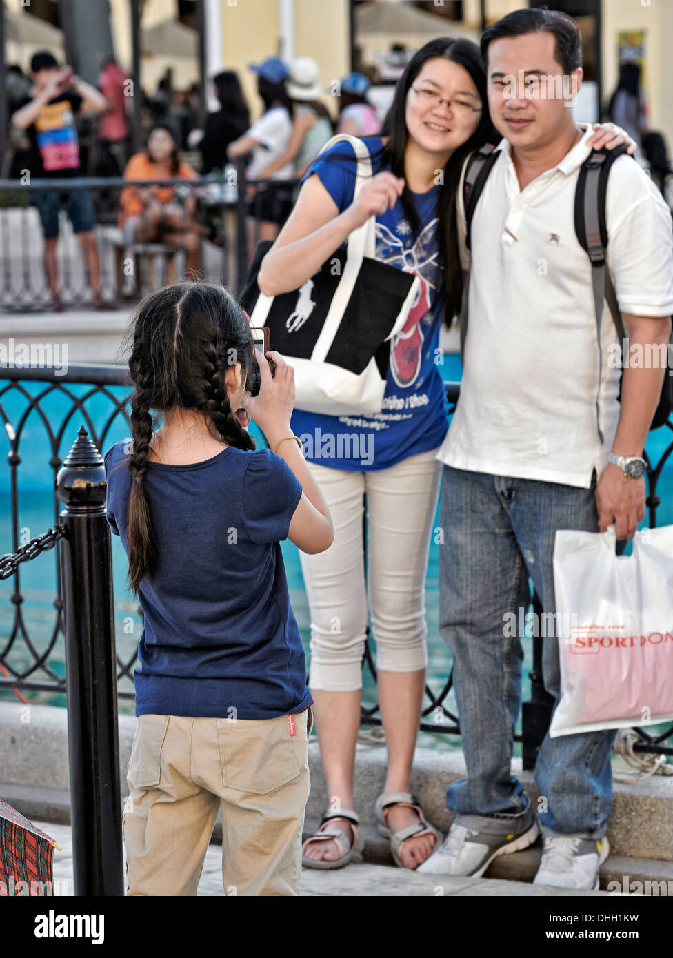 Asian child using a camera phone to photograph parents. Stock Photo