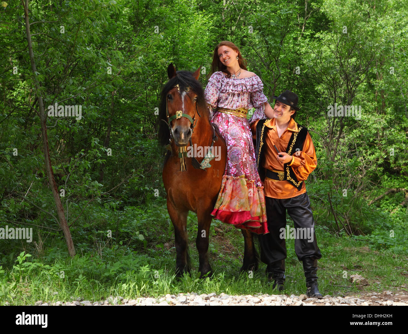 Roma and Gypsy woman walking through the woods with horse Stock Photo