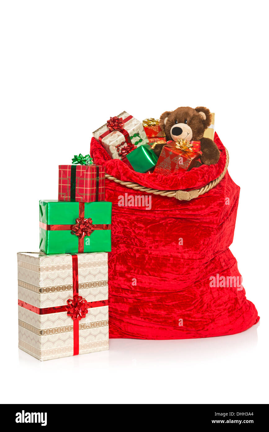 A red Christmas sack full of gift wrapped presents and toys, isolated on a white background. Stock Photo