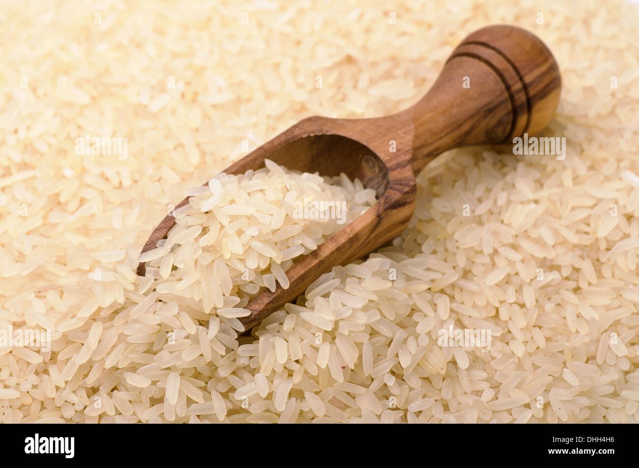 Wooden scoop on long grain rice Stock Photo