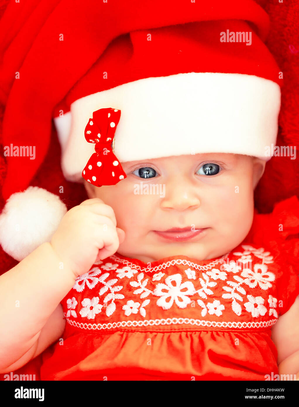 Closeup on beautiful newborn baby wearing red festive Christmas costume, Santa hat with decorative bow, New Year celebration Stock Photo