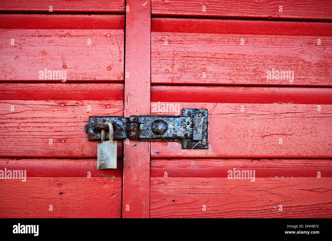 Padlock and latch on a red painted, wooden door. Stock Photo