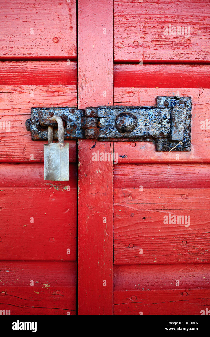 Padlock and latch on a red painted, wooden door. Stock Photo