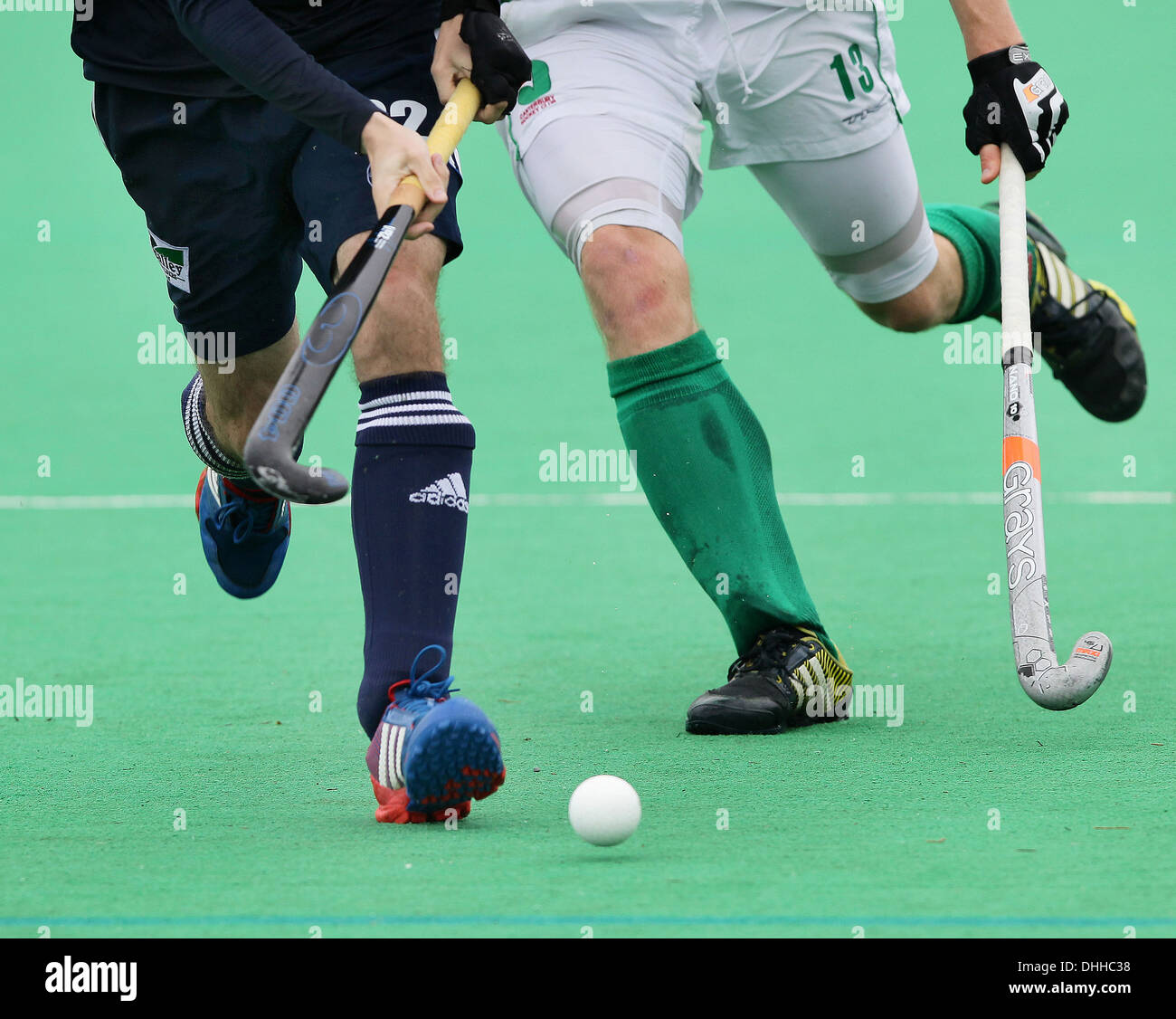 Waist down shot of two field hockey players with hockey sticks running towards the camera while competing for the ball. Stock Photo