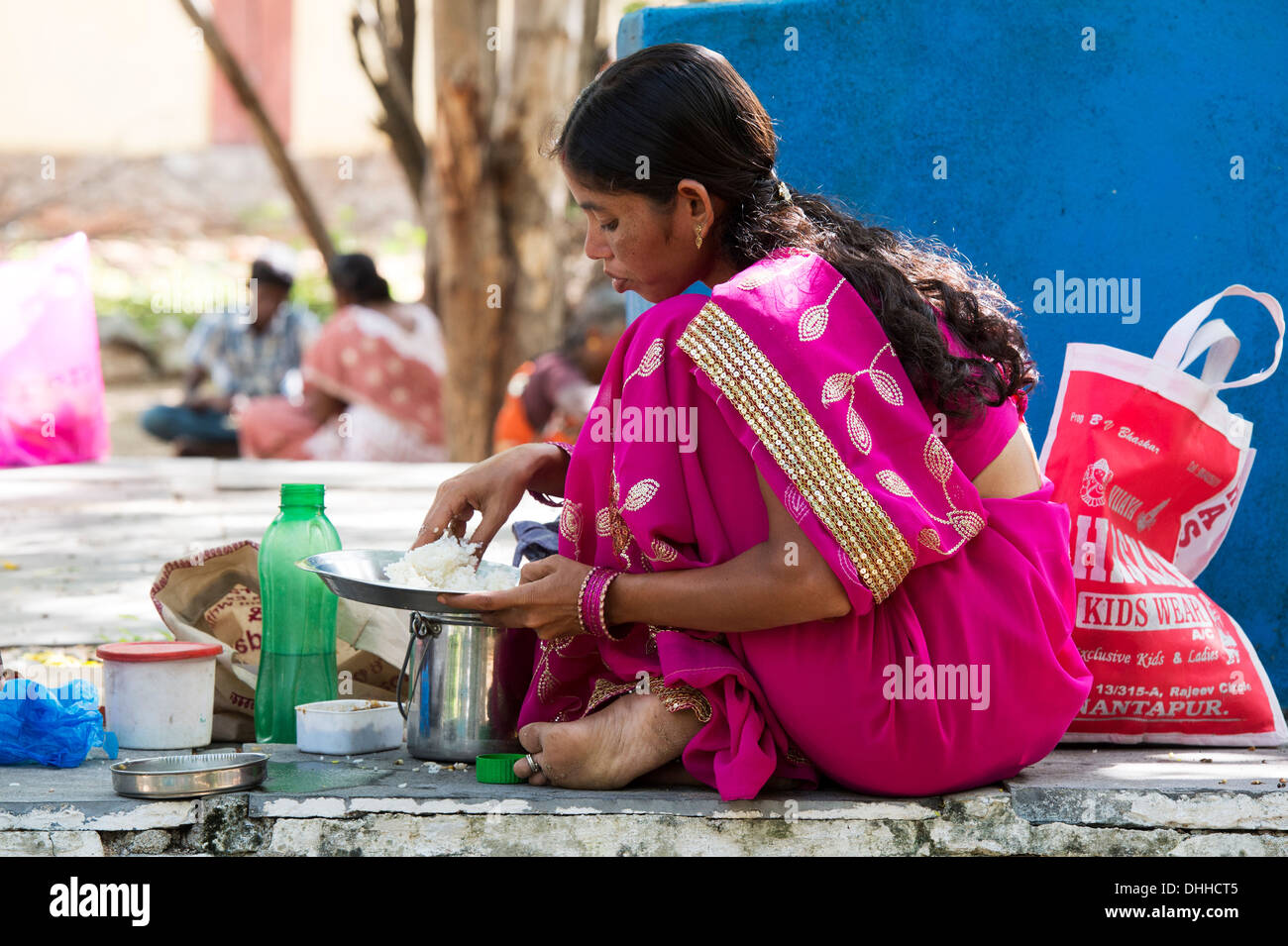 Indian woman wearing a pink sari eating a rice meal in a rural village. Andhra Pradesh, India Stock Photo