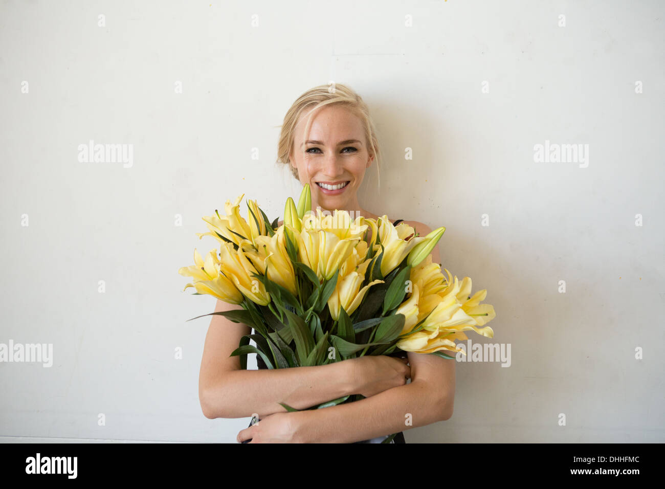 portrait of young woman holding bouquet of yellow flowers DHHFMC