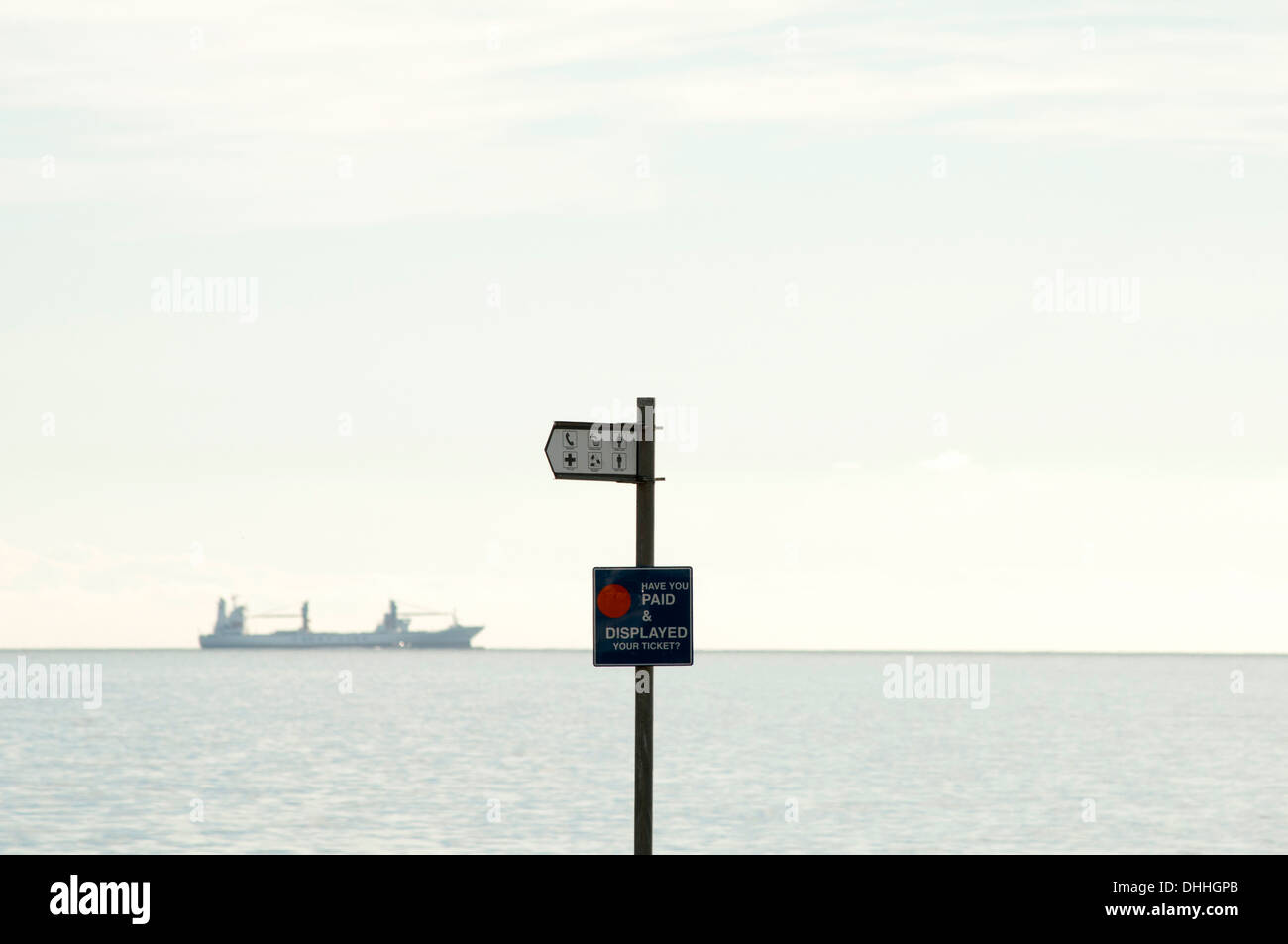 Ship on horizon with pay and display parking sign in foreground Stock Photo