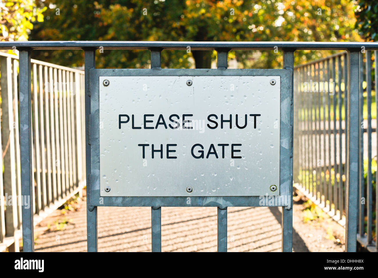 Metallic sign requesting people to shut the gate Stock Photo