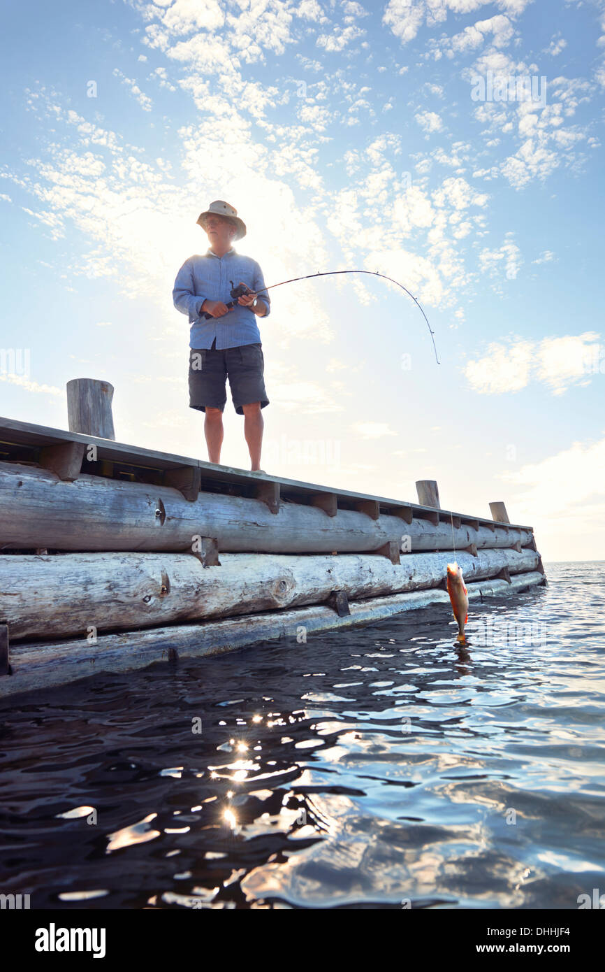 Senior man standing on pier with fishing rod, Utvalnas, Sweden Stock Photo