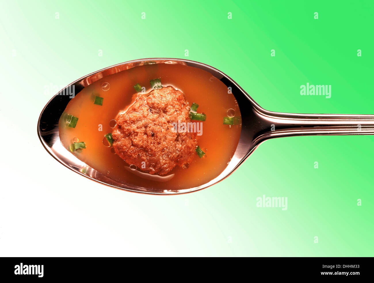 Meatball in broth on a silver spoon Stock Photo
