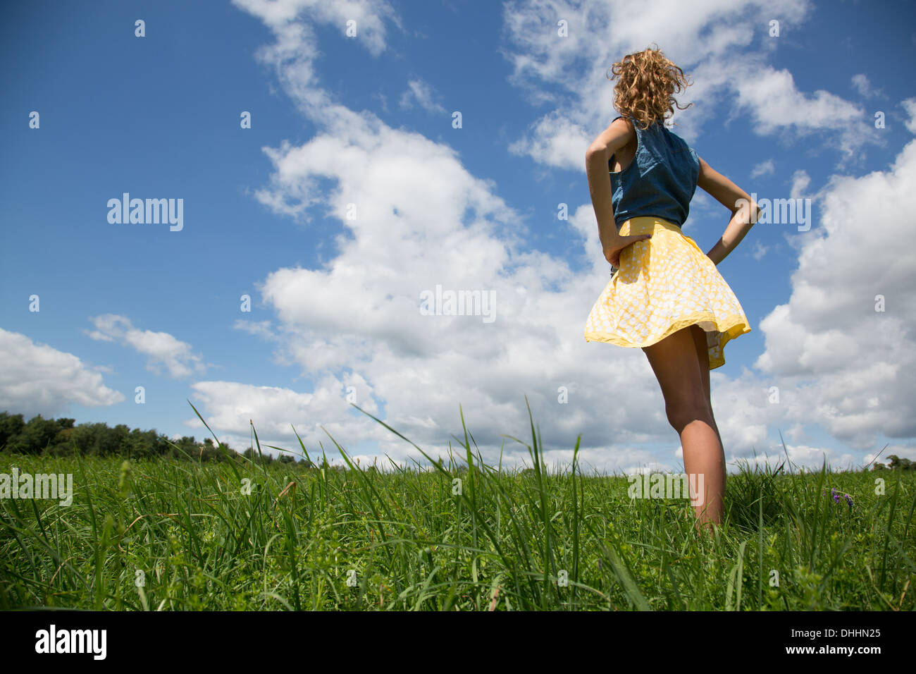 Teenage girl standing with hands on hips in field Stock Photo