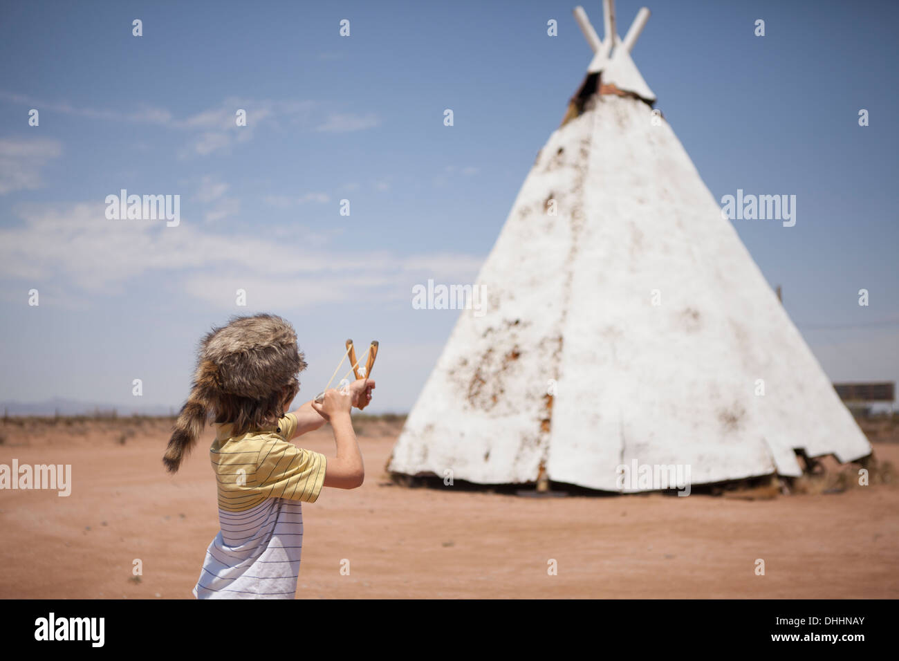 Boy aiming slingshot at teepee, Indian Reservation, USA Stock Photo
