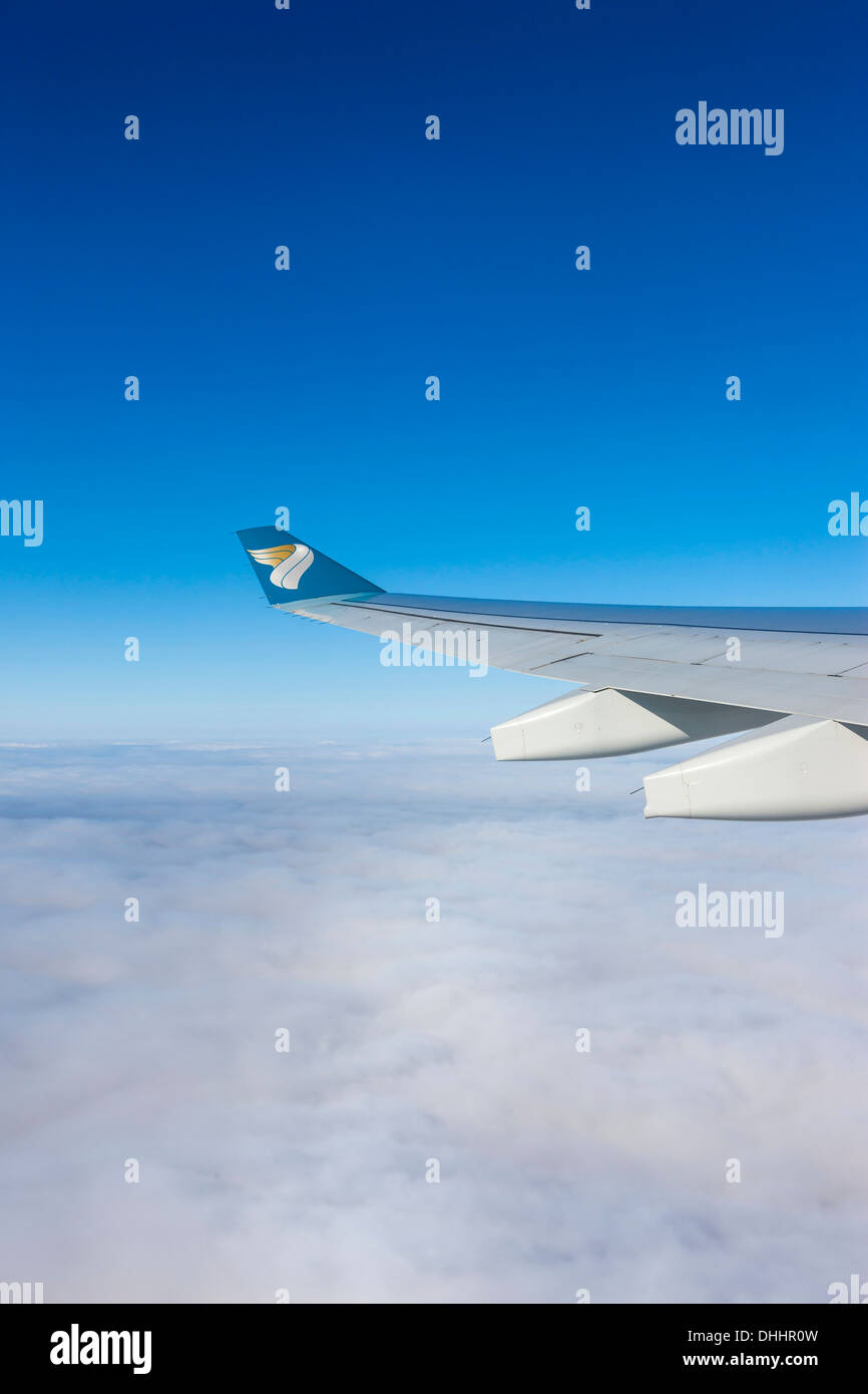 Wing of an Oman Air airplane above the clouds, Germany Stock Photo