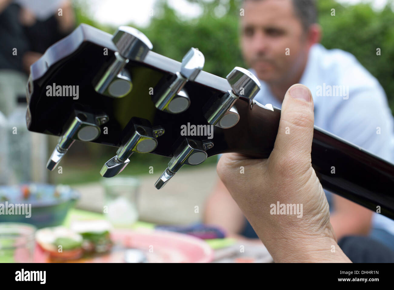 Close up of guitar, man in background Stock Photo