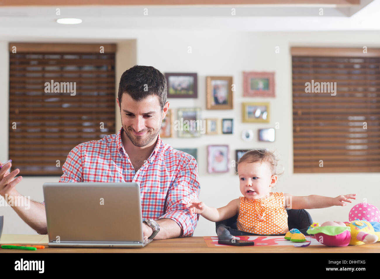 Man working at kitchen counter with baby sitting beside Stock Photo