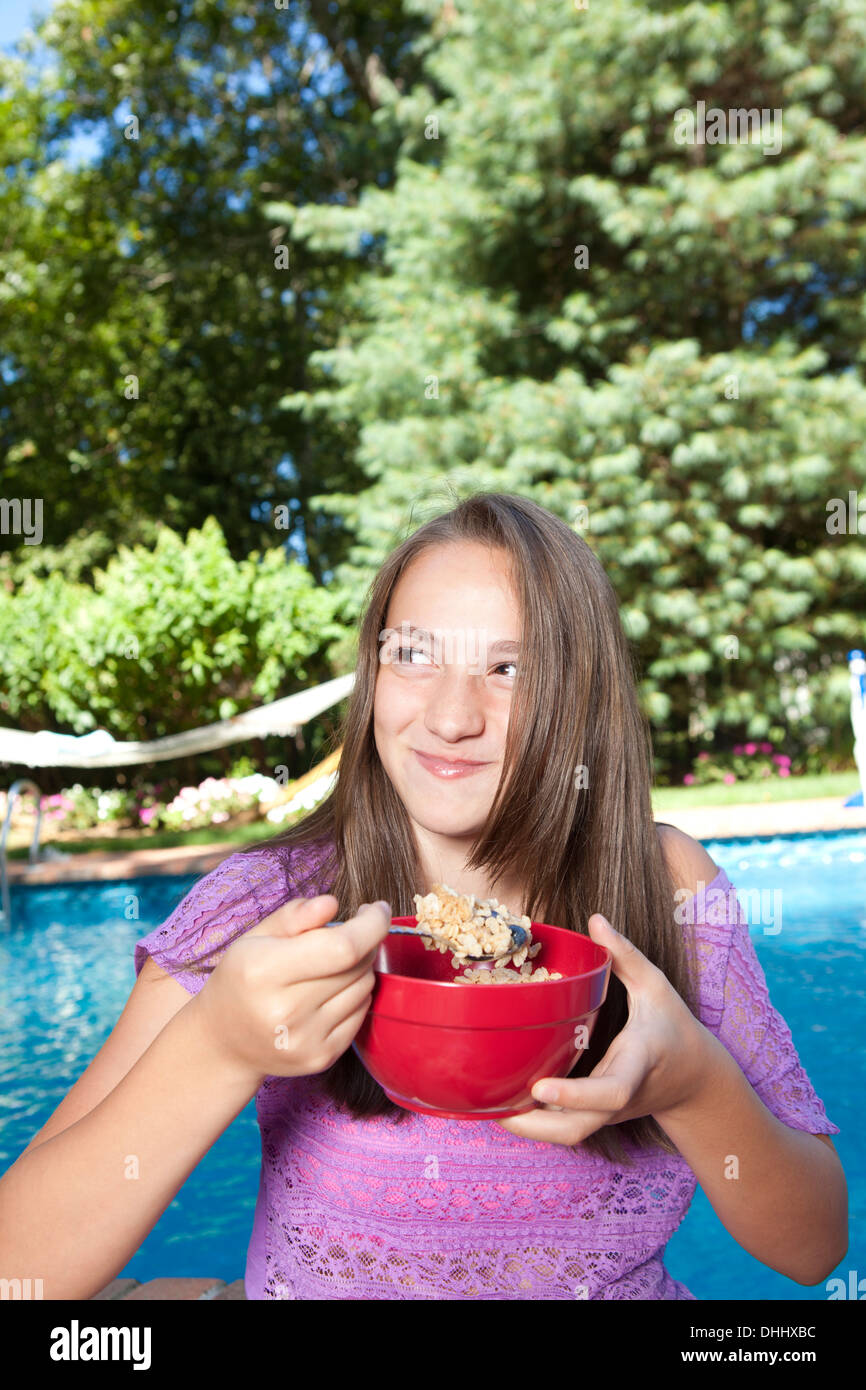 Girl eating by pool Stock Photo