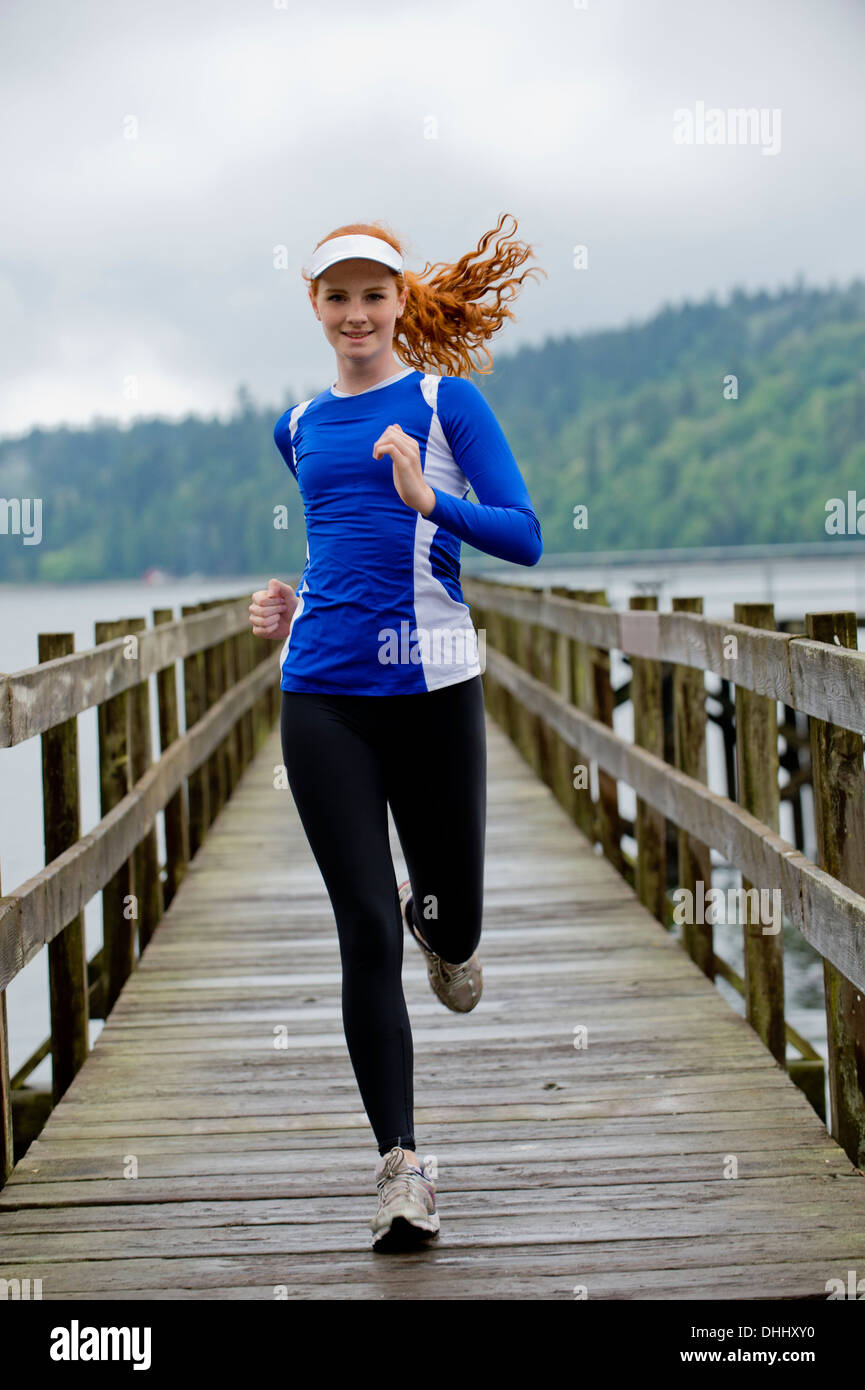 Teenage girl running on pier, Bainbridge Island, Washington, USA Stock Photo