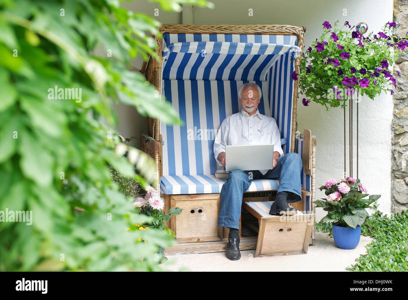 Senior man using laptop on garden seat Stock Photo