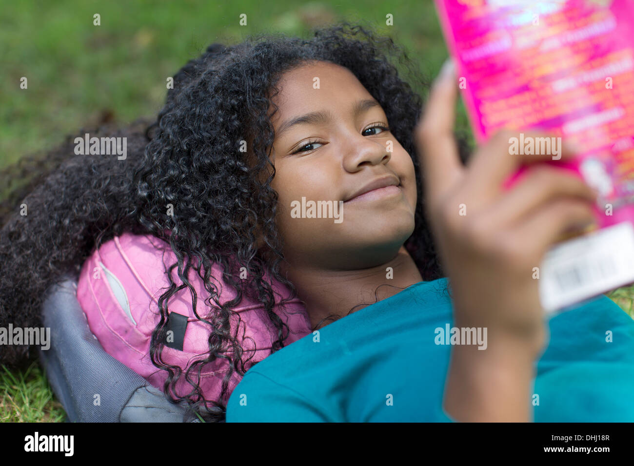 Close up portrait of young girl reading in park Stock Photo