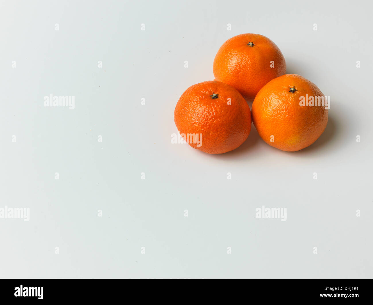 A trio of clementines sit on a white background in the top right with a