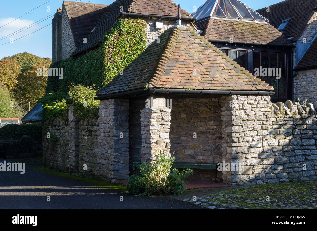 Bus shelter built from stone with a tiled pitched roof in Much Wenlock, Shropshire Stock Photo