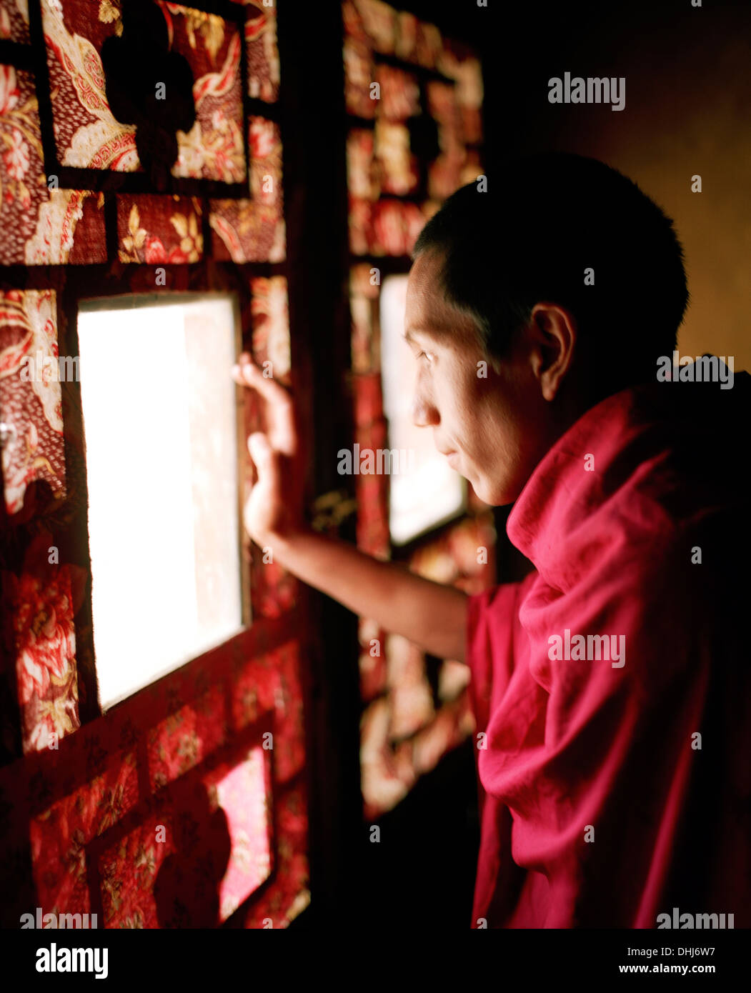 Monk looking out of a painted window, inner shrine at convent Rizong, founded in 1833, situated 3450m above sea level, 76 km wes Stock Photo