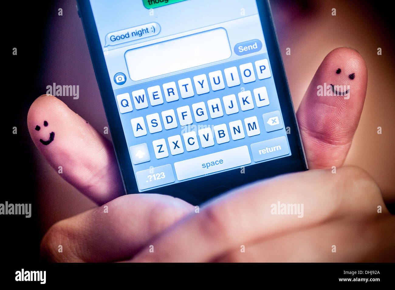 Pretty woman with smiles on thumbs texting good night with smartphone Stock Photo