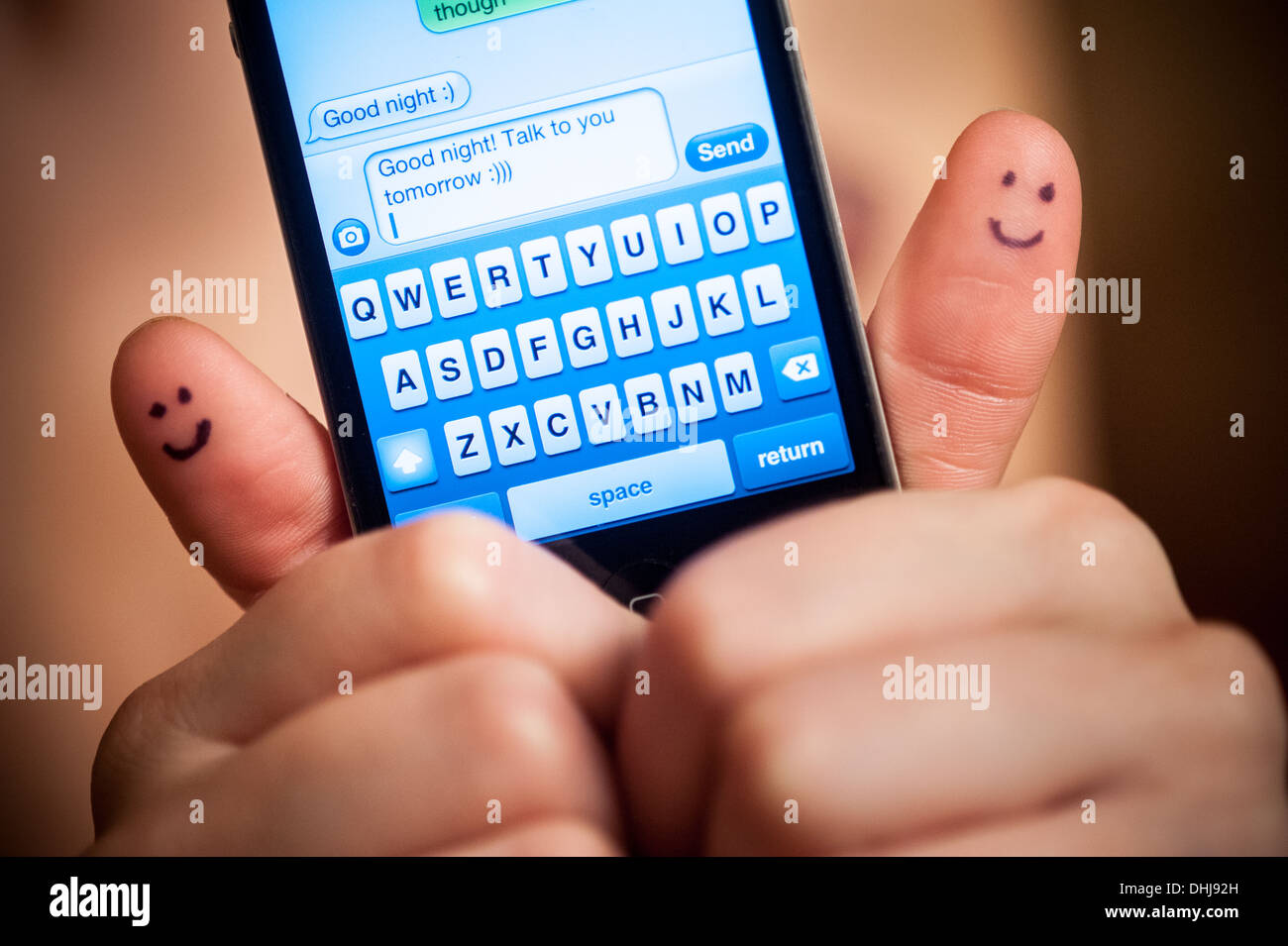 Pretty woman with smiles on thumbs texting good night with smartphone Stock Photo