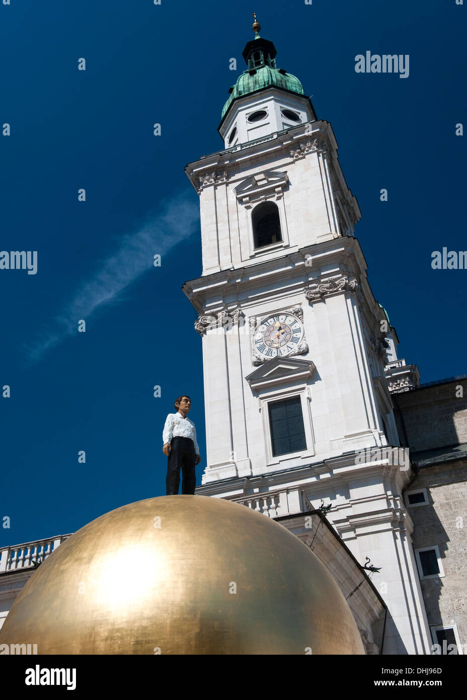 statue of man on large gold ball, in front of baroque church in Salzburg Stock Photo