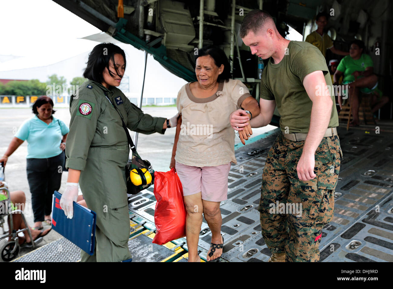 US Marines assist an injured Filipina woman off the back of a KC-130J Super Hercules transport aircraft at Villamor Air Base November 11, 2013 in Manila, The Philippines. The U.S. has joined relief efforts following the devastation caused by Super Typhoon Haiyan which is believed to have killed 10,000 people across the Philippine Islands. Stock Photo