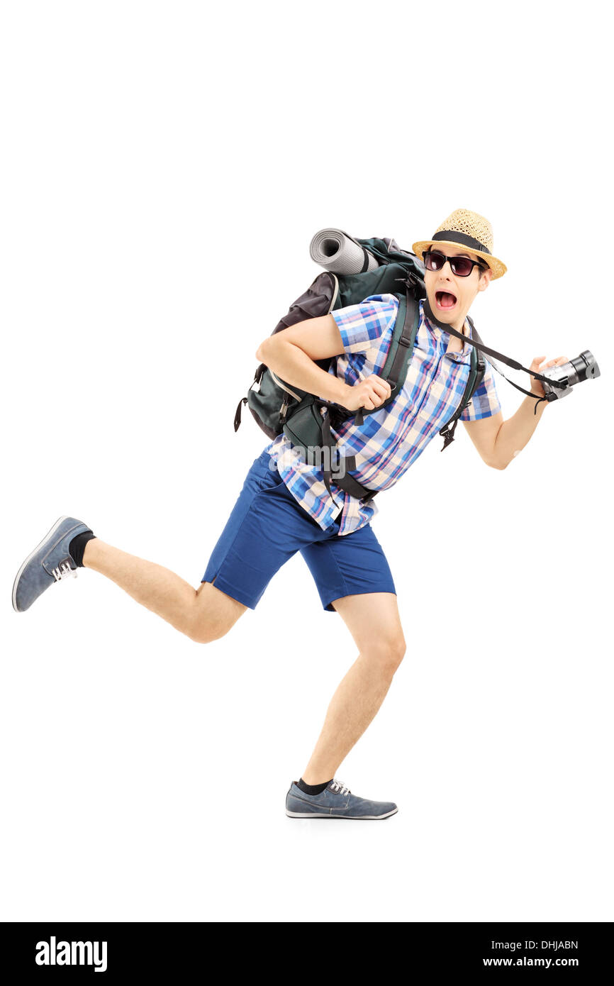Full length portrait of a scared hiker with backpack and camera running away Stock Photo