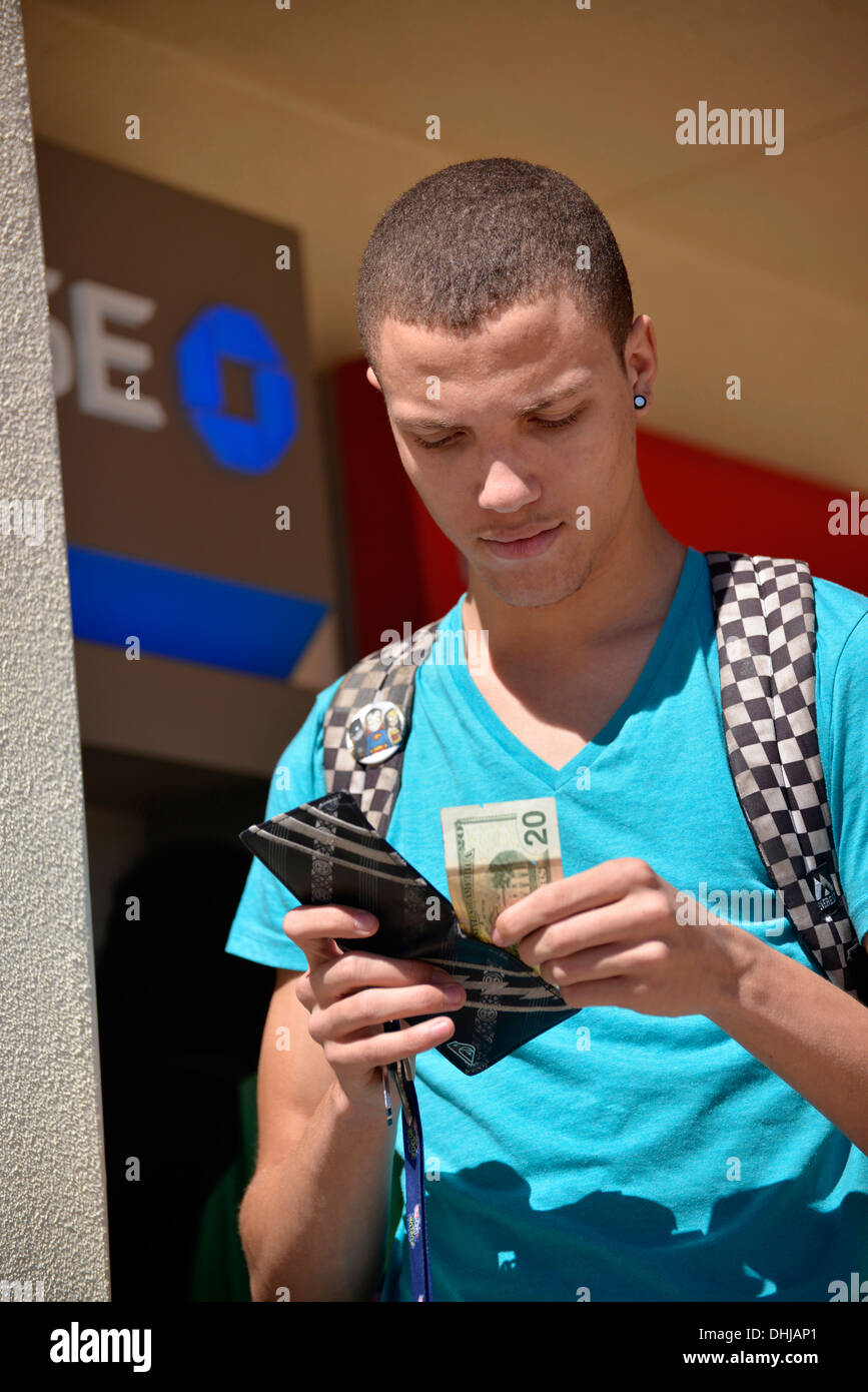A young man with a wallet and money on a college campus. Stock Photo