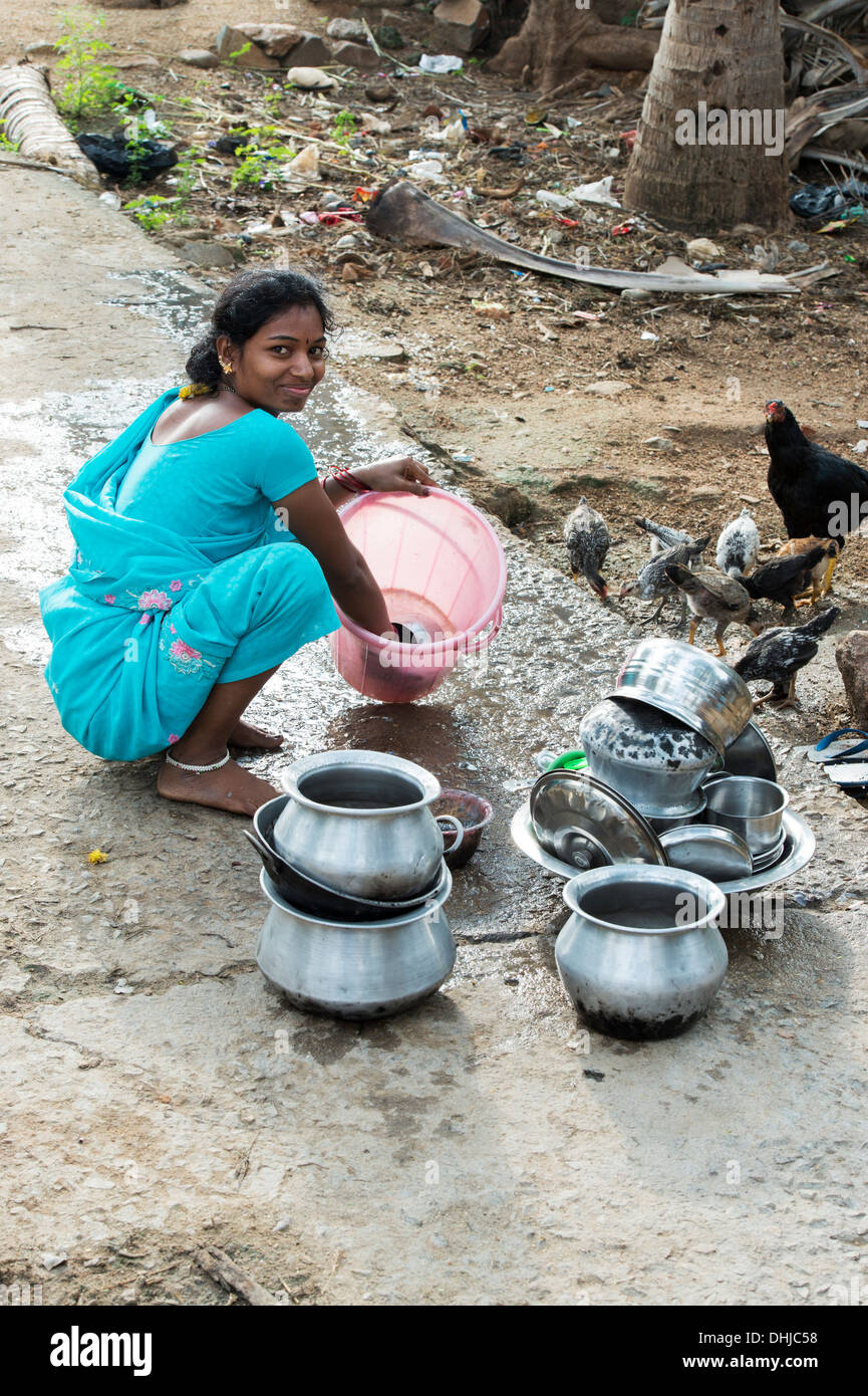 Young Indian woman washing dishes outside their rural indian village home. Andhra Pradesh, India Stock Photo
