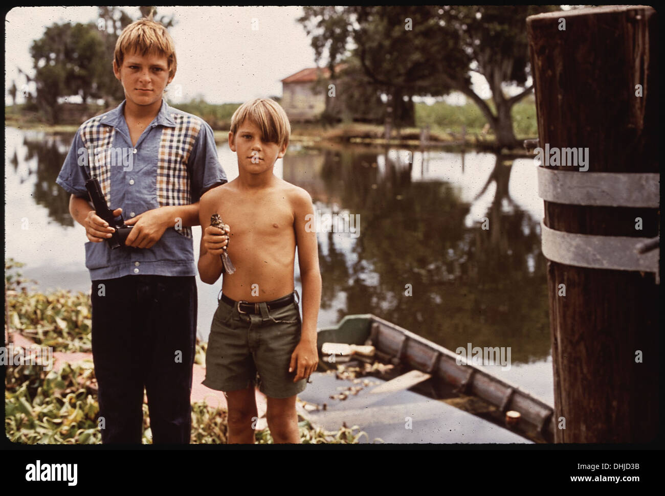 BOYS WITH AIRGUN AND BIRD. THESE FISHERMAN'S SONS LIVE IN BAYOU GAUCHE, DEEP IN THE WETLANDS OF LOUISIANA 194 Stock Photo