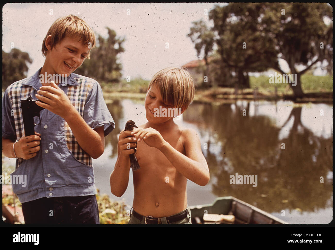 BOYS WITH AIRGUN AND BIRD. THESE FISHERMAN'S SONS LIVE IN BAYOU GAUCHE, DEEP IN THE WETLANDS OF LOUISIANA 211 Stock Photo