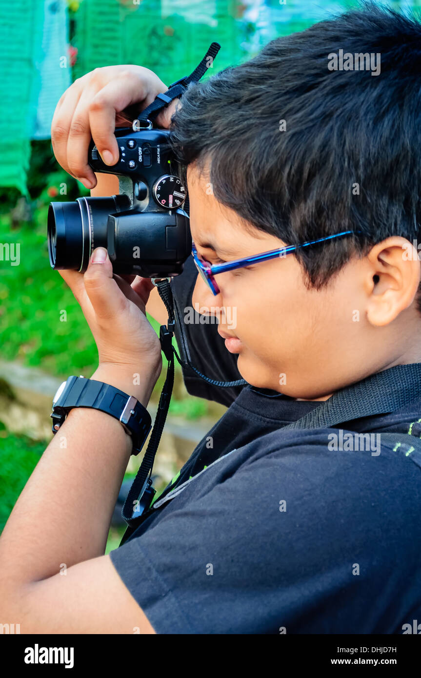 Little bespectacled Pre-adolescent Child , boy Photographing using a camera Stock Photo