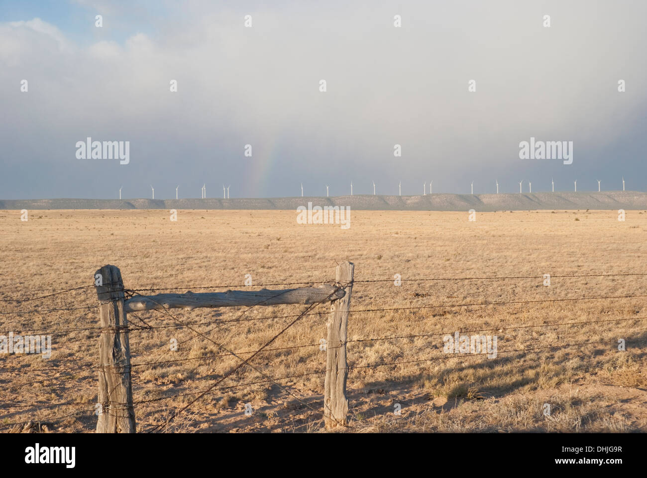 A faint rainbow resides above a row of wind turbines in New Mexico's