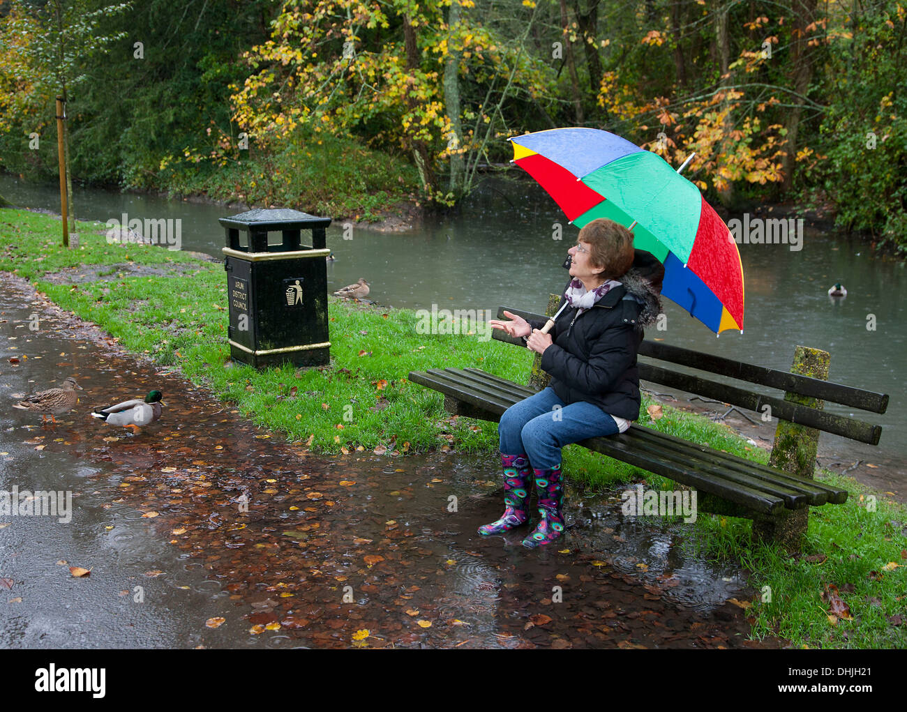 Lady sitting in rain under umbrella Stock Photo Alamy