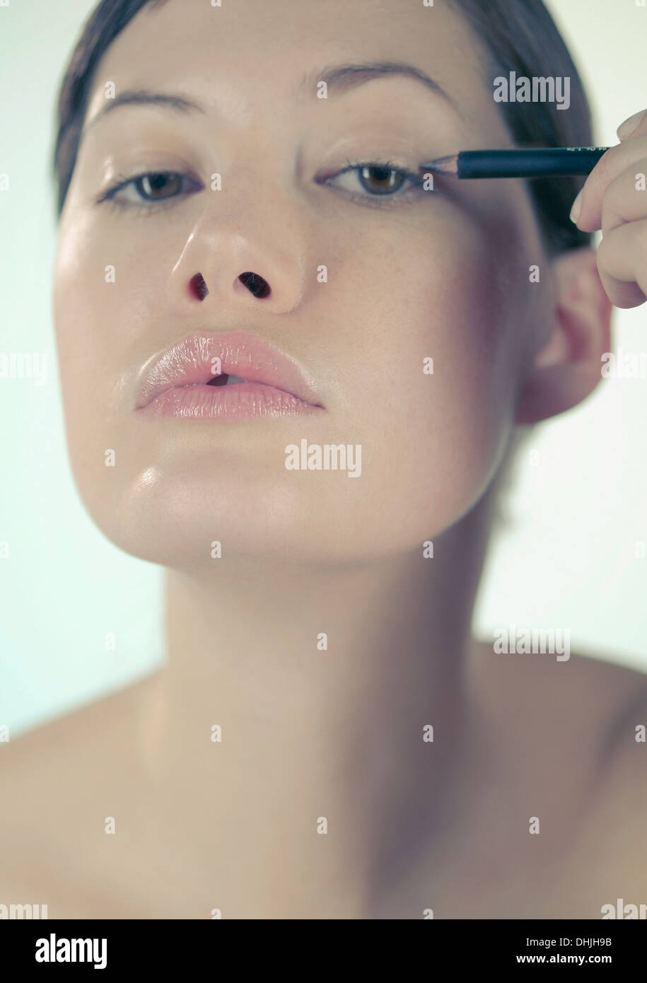 A young woman applying eyeliner Stock Photo